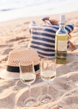 Glasses of the white wine on the sunset beach, picnic theme. Sea on the background